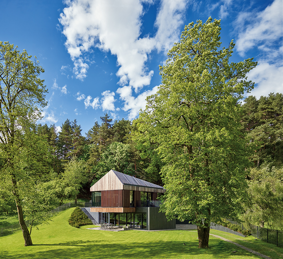 AyD-Arches(Vilnius)-e02. El proyecto establece una relación formal propia con el paisaje lituano, reelaborando la tipología local: un volumen limpio, con doble techo inclinado, persianas, acabados de madera y base de granito.