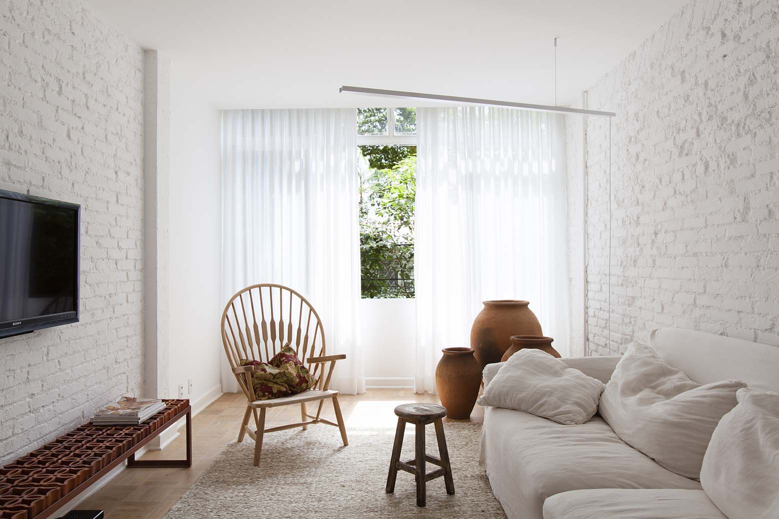01-sala. La pureza del blanco define a este apartamento que toma su nombre y su característica principal de los bloques cerámicos llamados cobogós. Creados en Brasil en 1930, estos bloques están presentes en diversos elementos de esta casa, como en el aparador situado bajo el televisor, diseñado también por el arquitecto Alan Chu