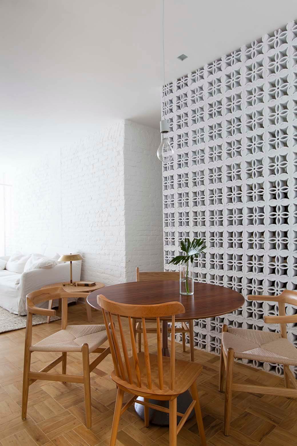 03-jantar. El cobogó, con su estético dibujo, se usa para componer paredes que separan ambientes, en este caso la cocina de la zona de comedor. Frente a esta pared, la mesa Carretel, de Ovo, y sillas de Artesian, con sus modelos Salt, C36 y Cowhorn