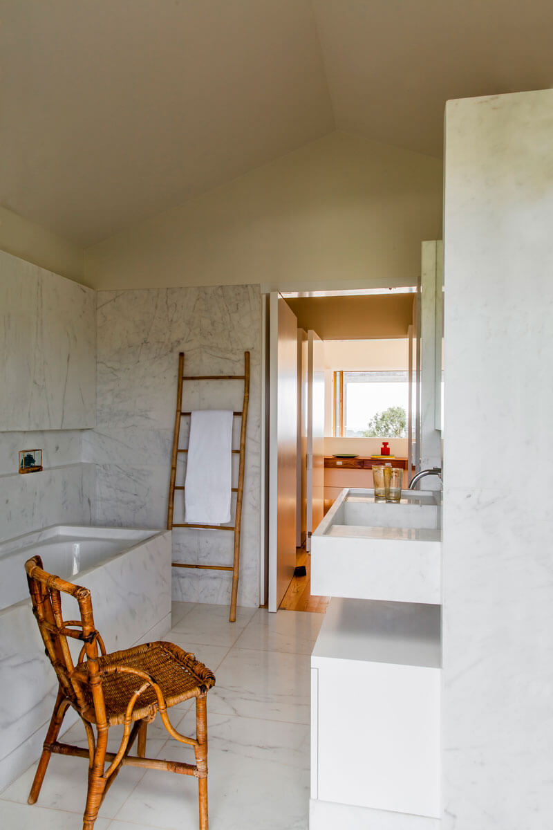 5-. En los baños se empleó mármol blanco para cubrir parte de las paredes y envolver la bañera. Un mueble a medida de madera lacada se diseñó a medida para guardar enseres de baño bajo el lavamanos
