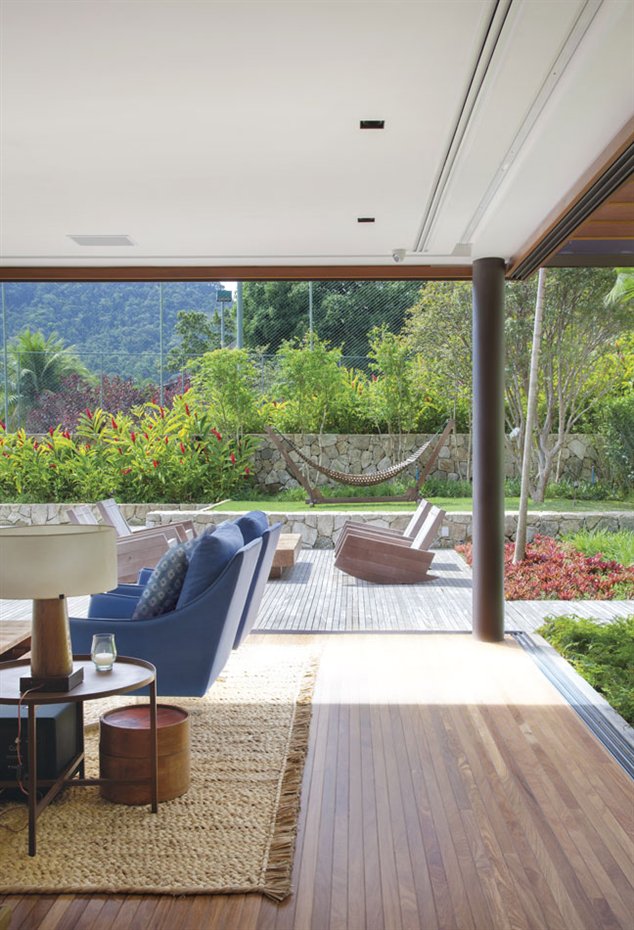 Jacobsen Arq2. Con puertas correderas de cristal, el área social se integra en la zona de piscina y jardín a través de una cubierta de madera