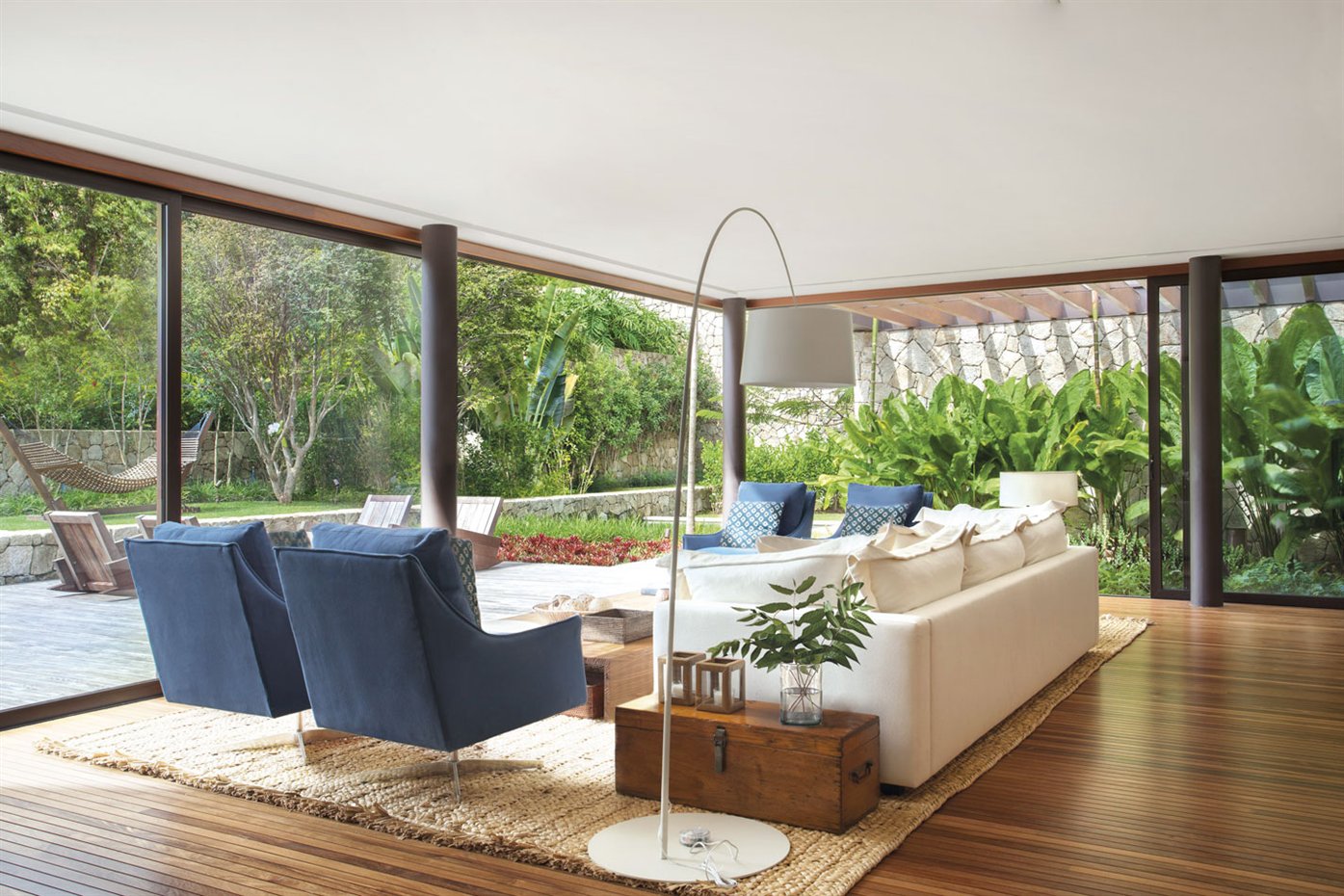 Jacobsen Arq3. La luz inunda la sala de estar, que está decorada con elementos y tejidos naturales como madera, algodón, cerámica o mimbre, y que dispone además de una pérgola con un muro de piedra envuelto de vegetación