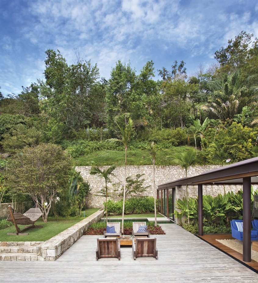Jacobsen Arq8. El jardín se integra a la perfección con el paisaje circundante, con vegetación típica de la zona y una piscina que se confunde con el verde de las plantas