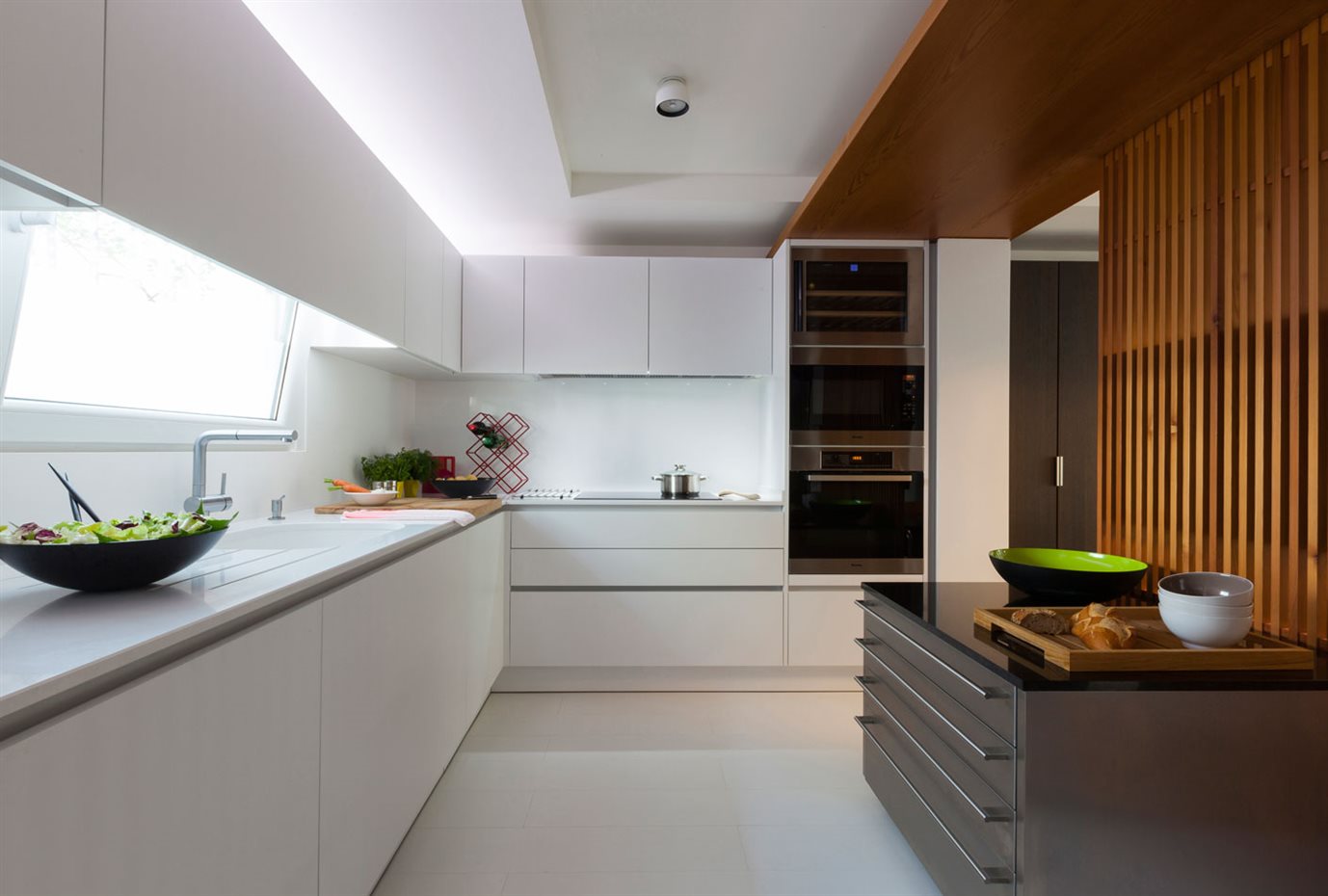 marbella4. La cocina es abierta en ambos extremos, favoreciendo la intercomunicación con el resto de la vivienda. La mampara corredera de listones de madera y dos islas auxiliares son los únicos elementos divisores