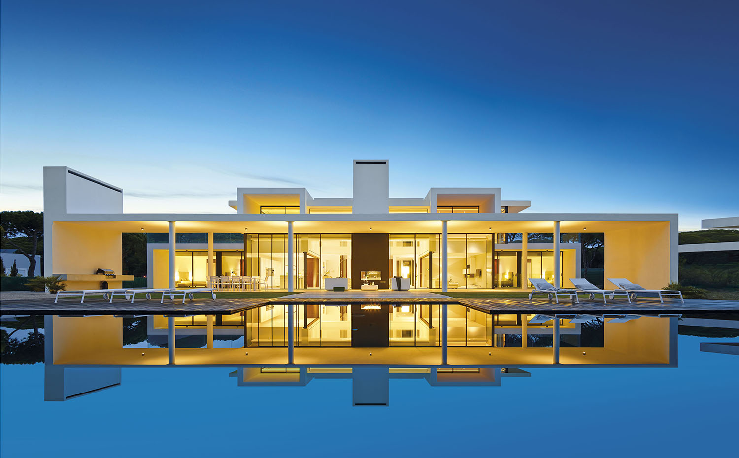 00358427 ok. De forma apaisada, la casa se descompone en cuerpos transparentes que multiplican su presencia reflejados en la lámina de agua de la piscina