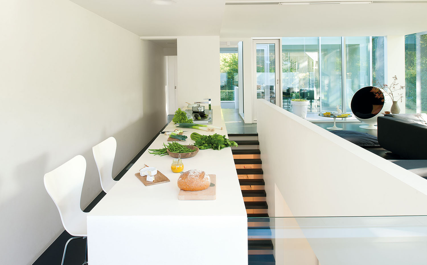 Mobiliario integral de cocina lacado de blanco y con encimera de Corian. Taburetes 7TM Bar Stool, de Arne Jacobsen para Fritz Hansen