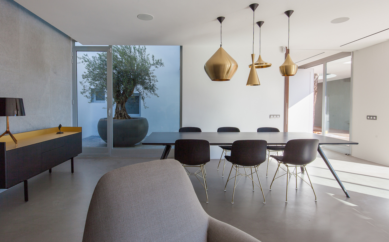 IMG 8965. Sobre la mesa del comedor Evans, de Minotti, cuelgan las lámparas Beat de latón dorado, de Tom Dixon. Las sillas son de la colección Troy, de Magis. Lámpara Lumiere XXL, de Foscarini, sobre aparador Stockholm, de Mario Ruiz para Punt 