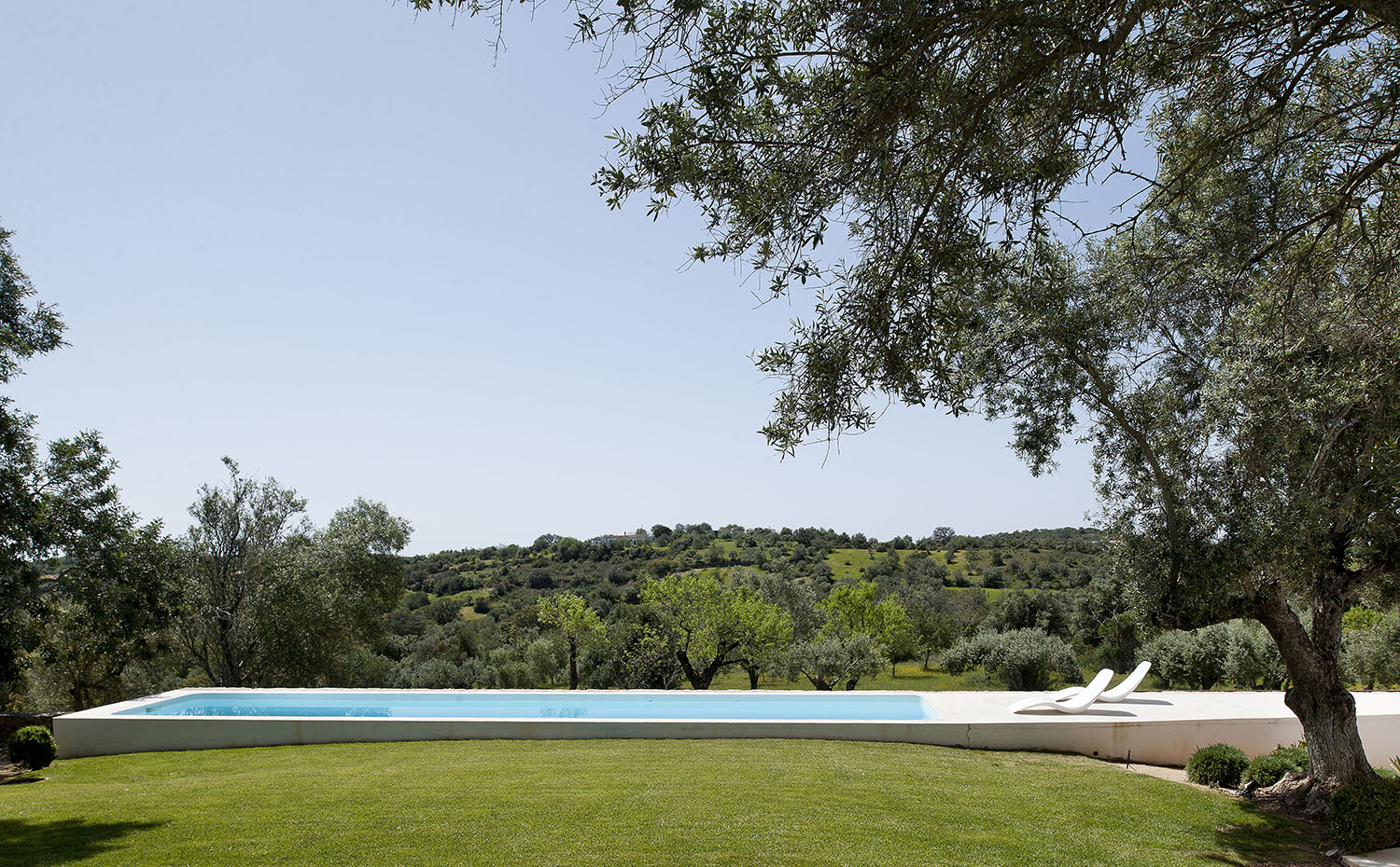 La plataforma de hormigón que rodea la piscina se prolonga en una terraza-solárium