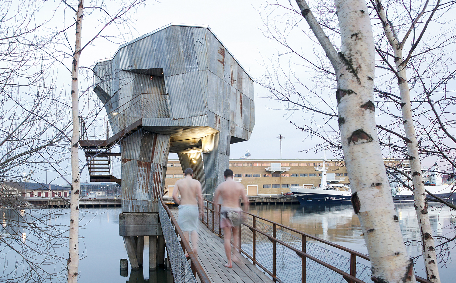 Raumlabor Göteborg bathing culture. Por fuera, la sauna de Gotemburgo está recubierta con planchas metálicas onduladas recicladas, reminiscencia del entorno industrial. Se accede a ella a través de una pasarela de madera