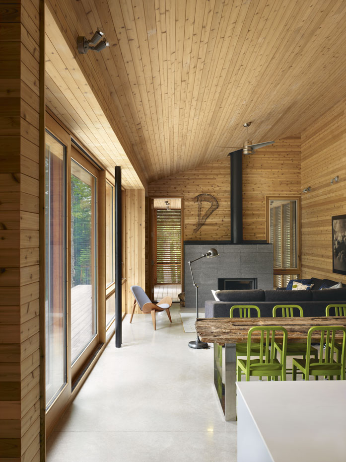 superkul Stealth-Cabin hi 11. El revestimiento de madera y una mesa "sin tratar" nos recuerdan que nos encontramos en el interior de una cabaña, un proyecto de Superkül Architects 