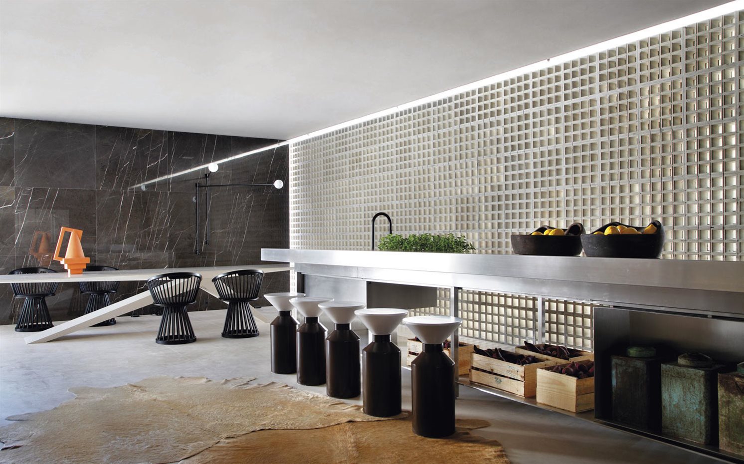 VILLA-DECA STUDIO-GT-(54). La cocina de estética industrial es un diseño de Guilherme Torres, al igual que los taburetes Milk, que edita Nos. Alrededor de la mesa de comedor, las sillas Fan, de Tom Dixon