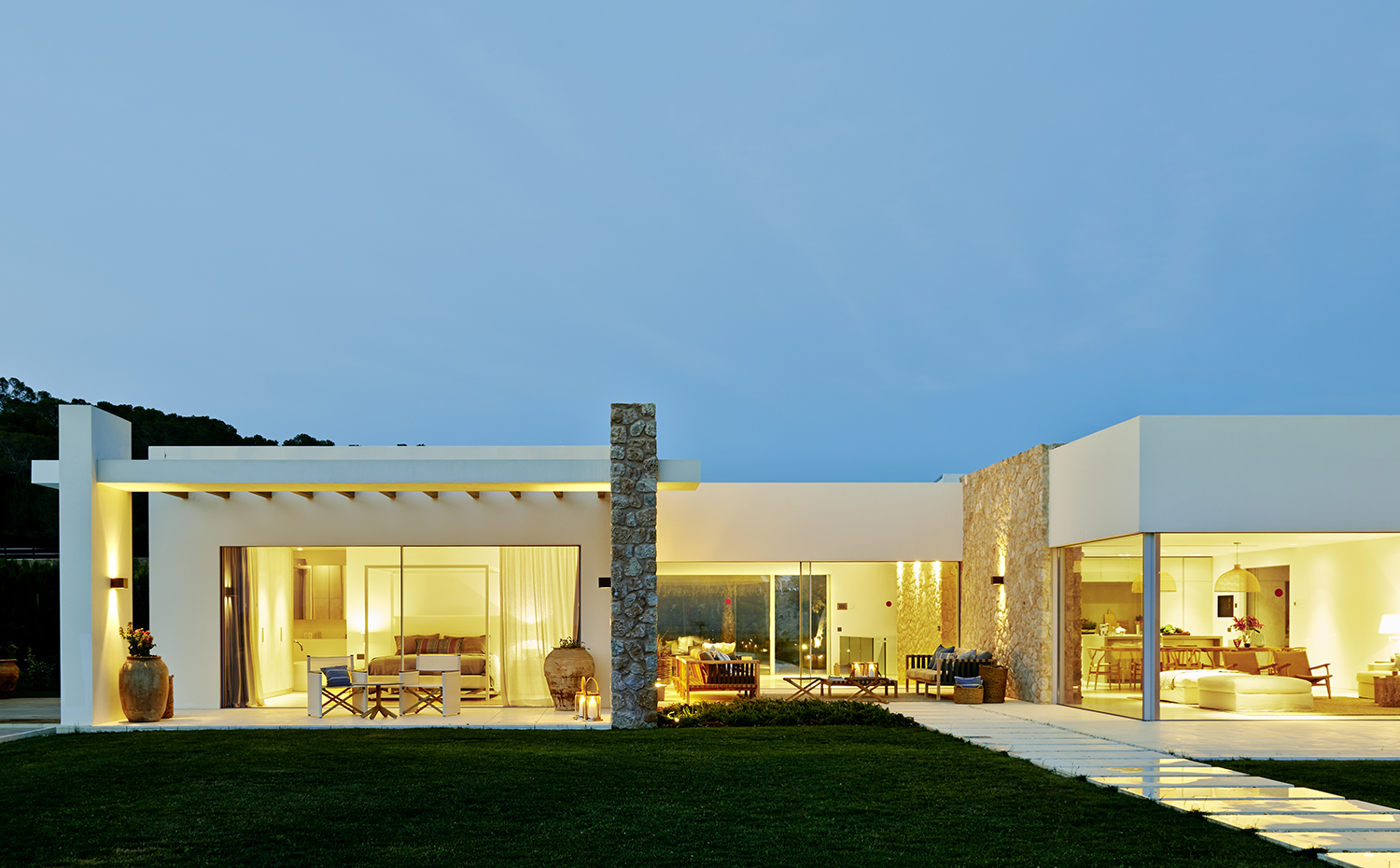00387570 ok. La casa se integra en el paisaje, con su fachada de monocapa blanco y sus muros de mampostería en piedra marés