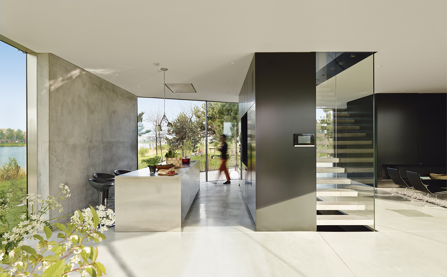 00387748 ok. Los taburetes de la cocina son el modelo Bombo, diseño de Stefano Giovannoni para Magis. La escalera de acceso al nivel superior está resuelta con peldaños sin contrahuella que se apoyan en el bloque que contiene el mobiliario de cocina, a un lado, y un paño de cristal al otro