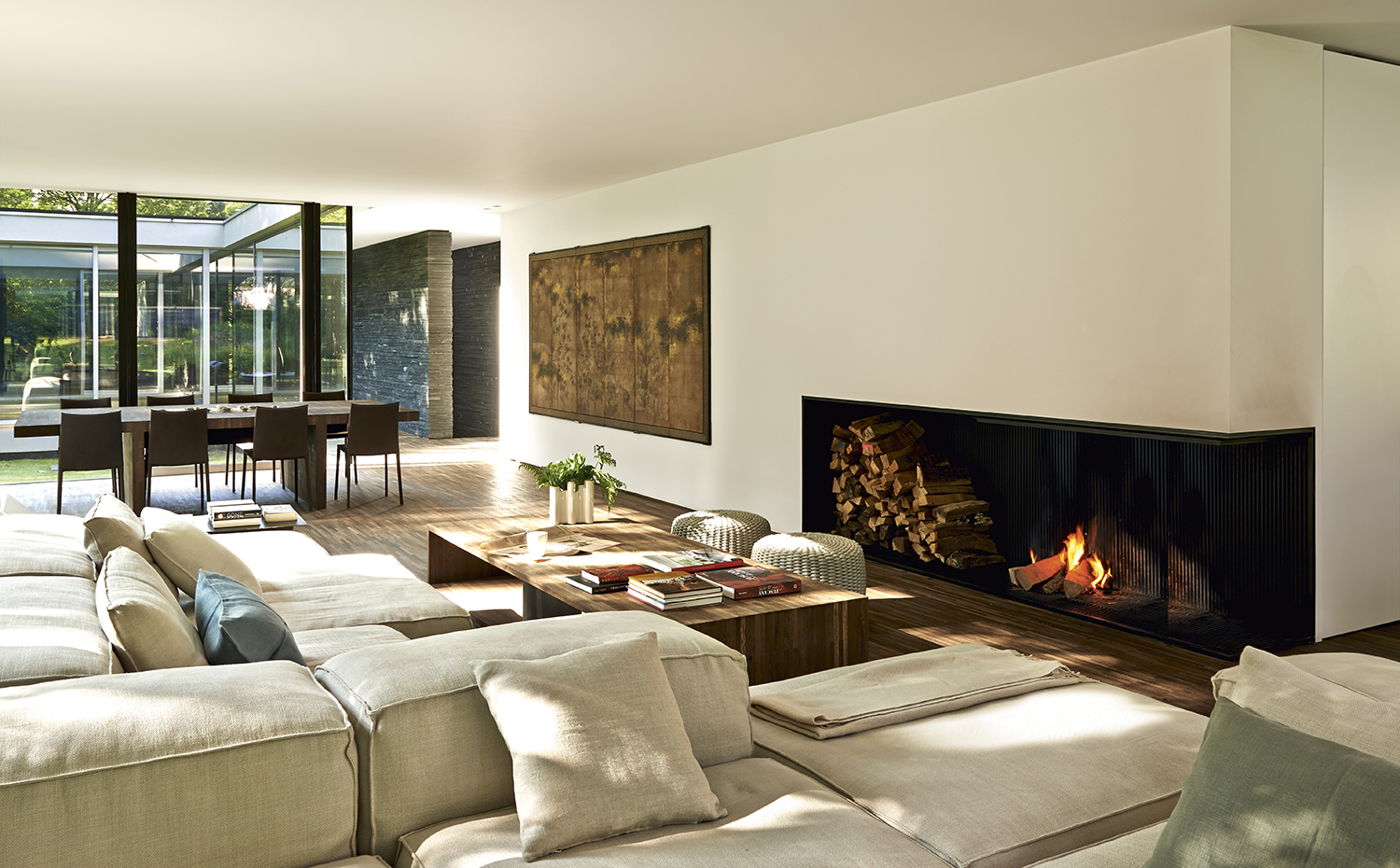 00388626 ok. La zona de comedor se ha ubicado pegada a las cristaleras del perímetro, mientras que el salón se ordena en torno a la chimenea. La mesa de centro es un diseño del arquitecto realizado con madera de wengué