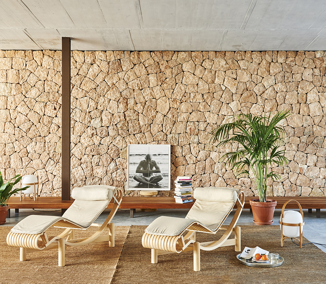 00395131 ok. Sobre la alfombra de sisal, dos chaise-longue, modelo Tokio, diseño de Charlotte Perriand para Cassina, y la lámpara Cesta, de Miguel Milá para Santa & Cole. El banco de madera de iroco es un diseño de Estudio Marcos Catalán
