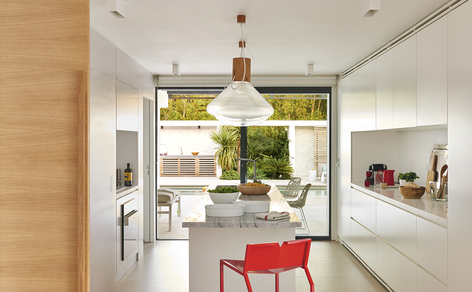 00398195 ok. El mobiliario integral de la cocina es un diseño de Vincent Coste, al igual que el taburete rojo. Grifería de Grohe. Sobre la encimera de la isla, piezas de cerámica blanca, de Alessi