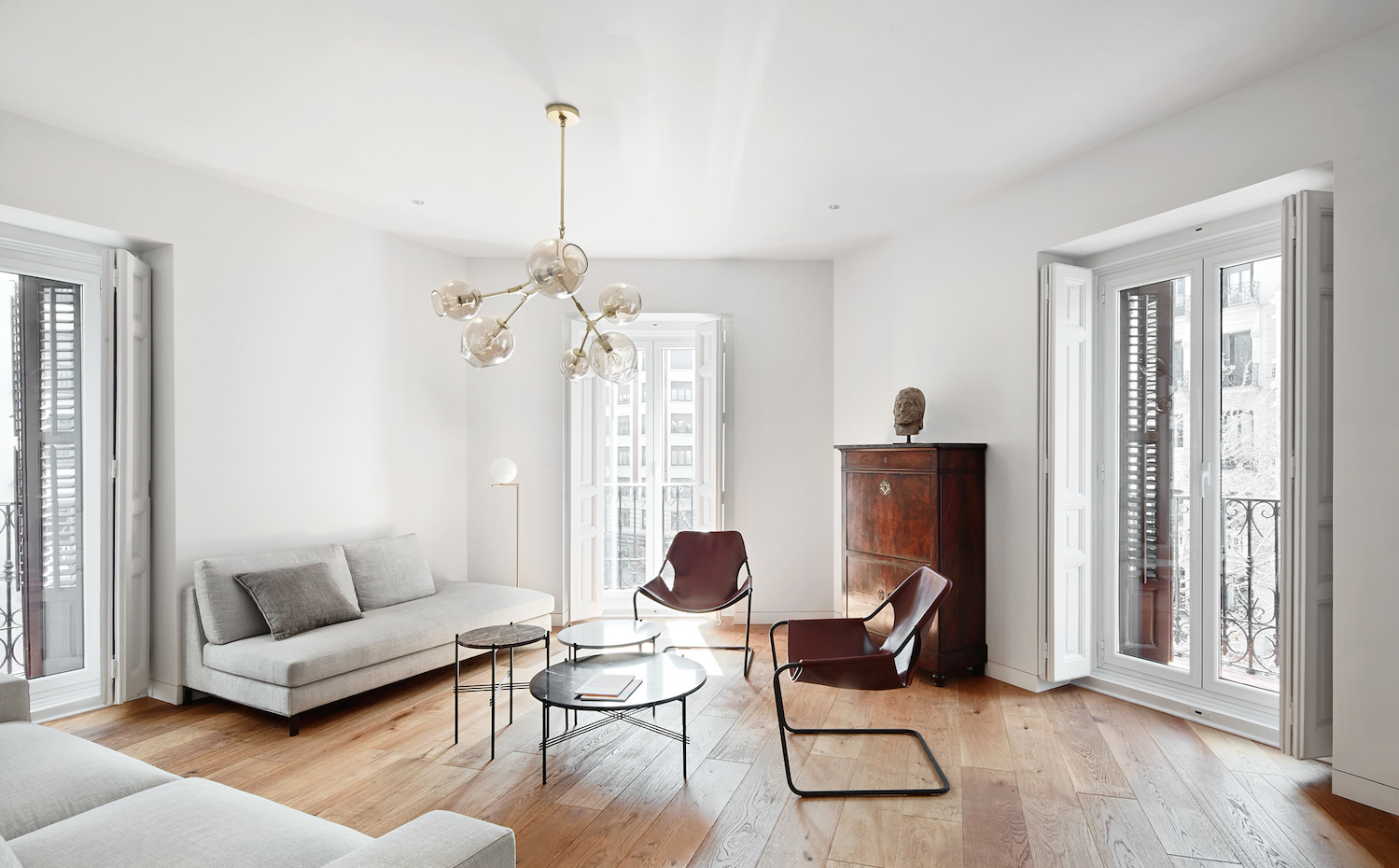 PRINCIPE-VERGARA-12. La sala de estar coincide con la esquina de la fachada en chaflán; tiene por tanto tres balcones y una original geometría. Butacas Paulistano, de Paulo Mendes da Rocha y comercializadas por Objekto
