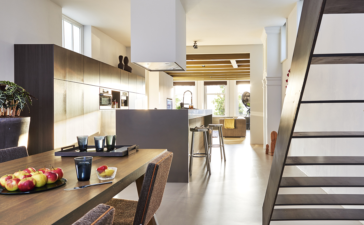 00407714 ok. La nueva escalera, de acero pintado, es un ejemplo de artesanía contemporánea. Sobre la mesa de comedor, vasos de colores, de Iittala