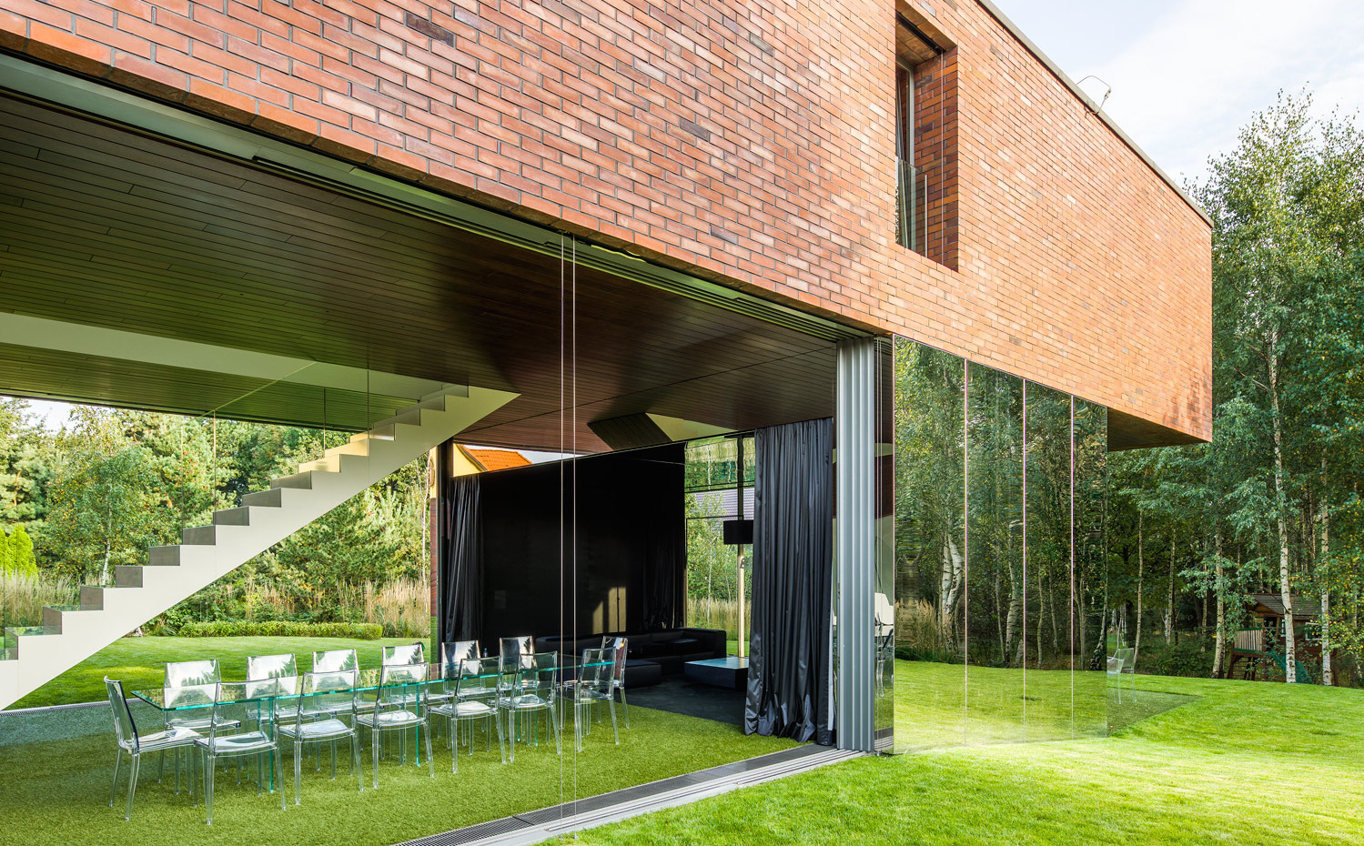 05 photo-Jakub-Certowicz Living-Garden-House-in-Katowice Robert-Konieczny-KWK-Promes. En el salón comedor, la ligereza y la presencia del exterior son extremas: el suelo es de césped y la mesa y la silla son transparentes para conseguir que el jardín se vea aún más si cabe