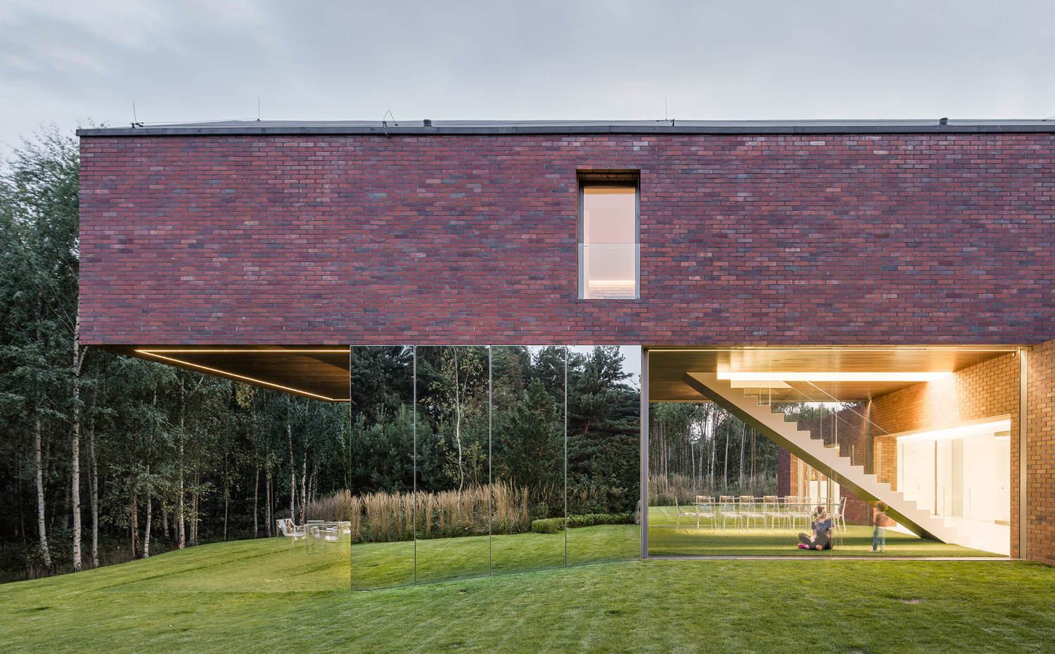 10 photo-Jakub-Certowicz Living-Garden-House-in-Katowice Robert-Konieczny-KWK-Promes. Un enorme espejo consigue que el césped del jardín quede perfectamente reflejado en la fachada y se integre creando la ilusión de que una pared de cristal más larga que soporta la estructura superior de la casa