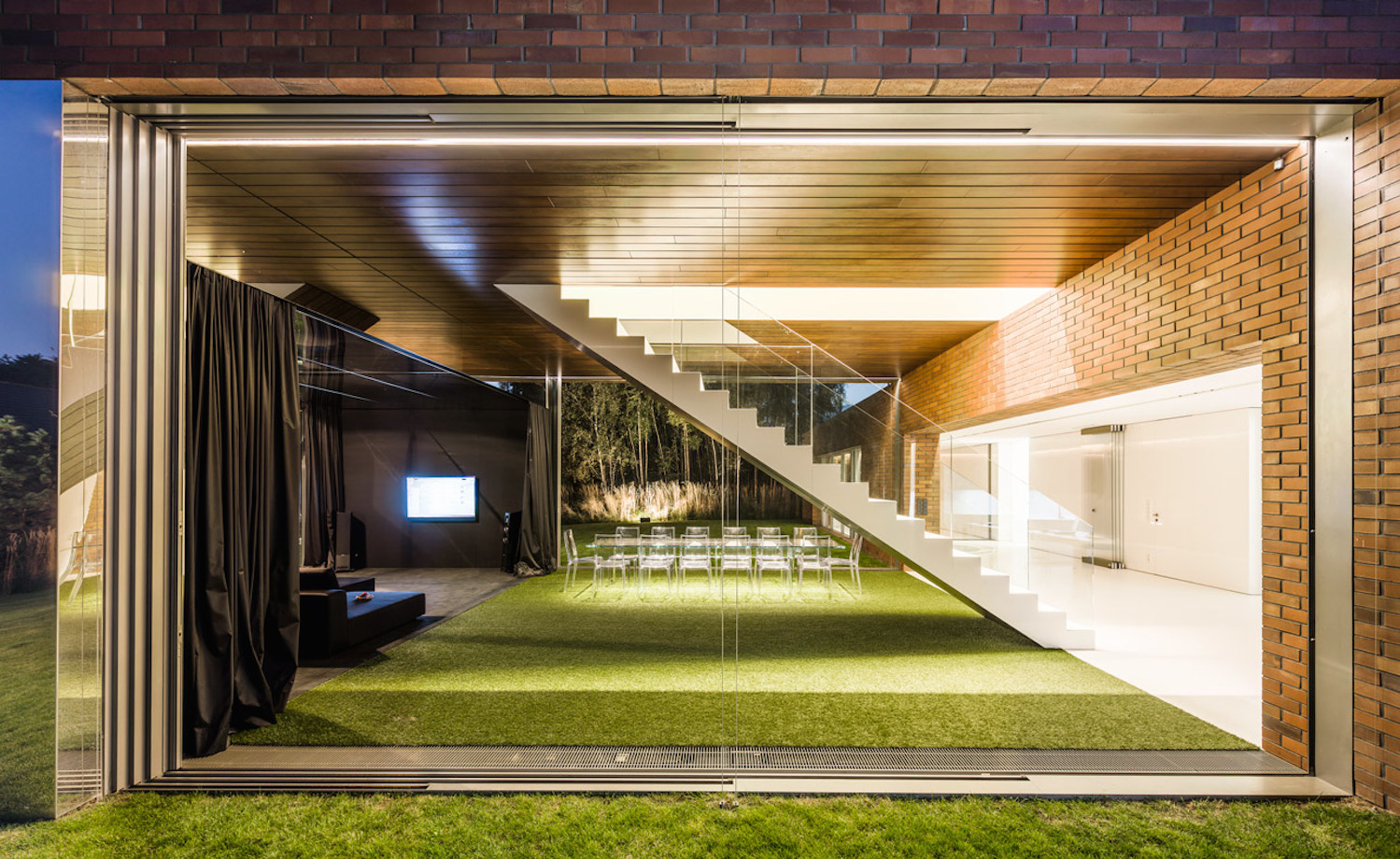 18 photo-Jakub-Certowicz Living-Garden-House-in-Katowice Robert-Konieczny-KWK-Promes. De noche, mientras el salón comedor integrado en el jardín está iluminado muy discretamente, la luz artificial que llega de la zona de noche es abundante y llama al cambio: toca pasar a la zona de arriba