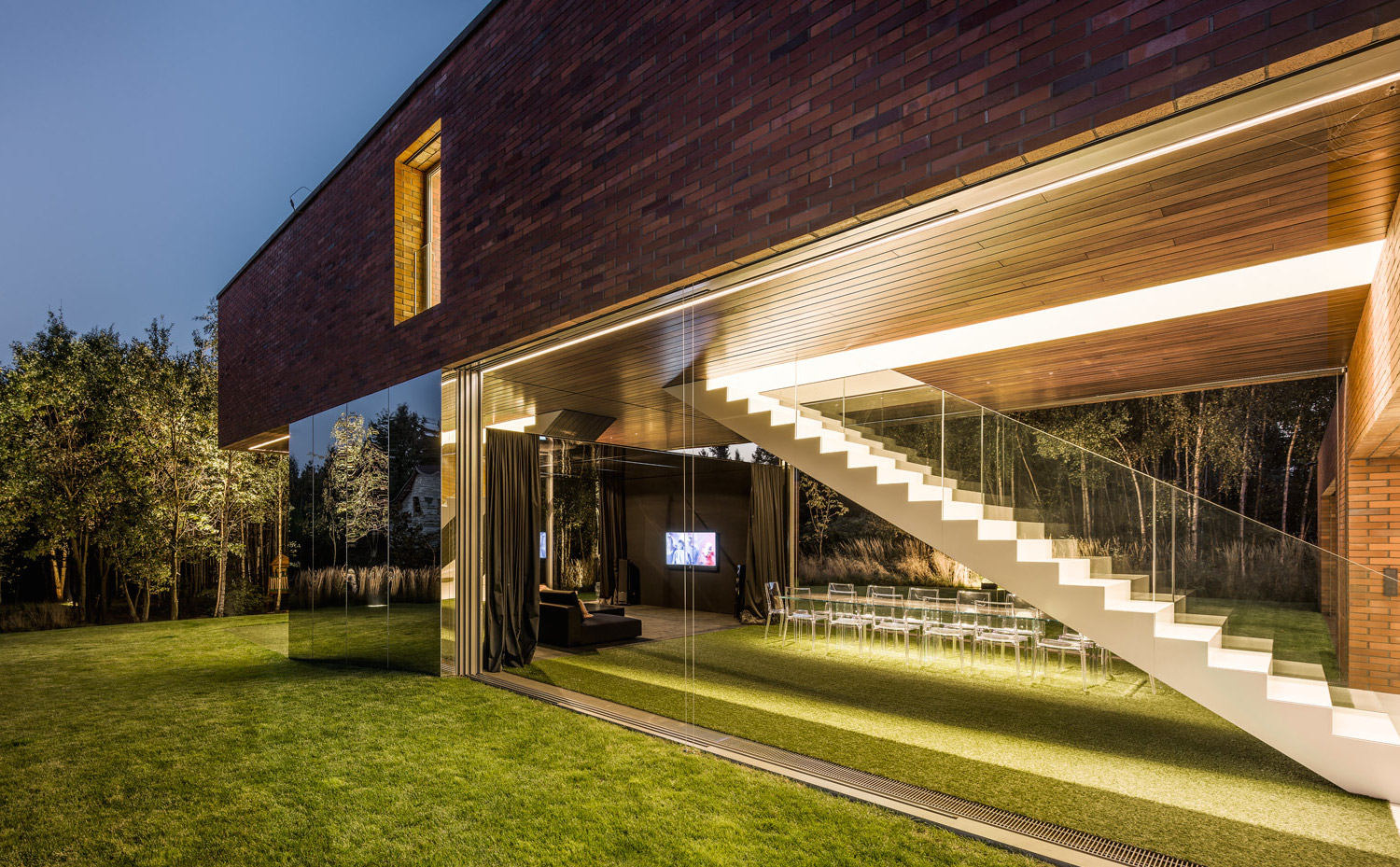11 photo-Jakub-Certowicz Living-Garden-House-in-Katowice Robert-Konieczny-KWK-Promes. Al colocar el espejo que refleja el césped de forma contigua al cristal de la fachada, la sensación generada es de que el jardín es eterno y que la zona de arriba queda suspendida en el aire