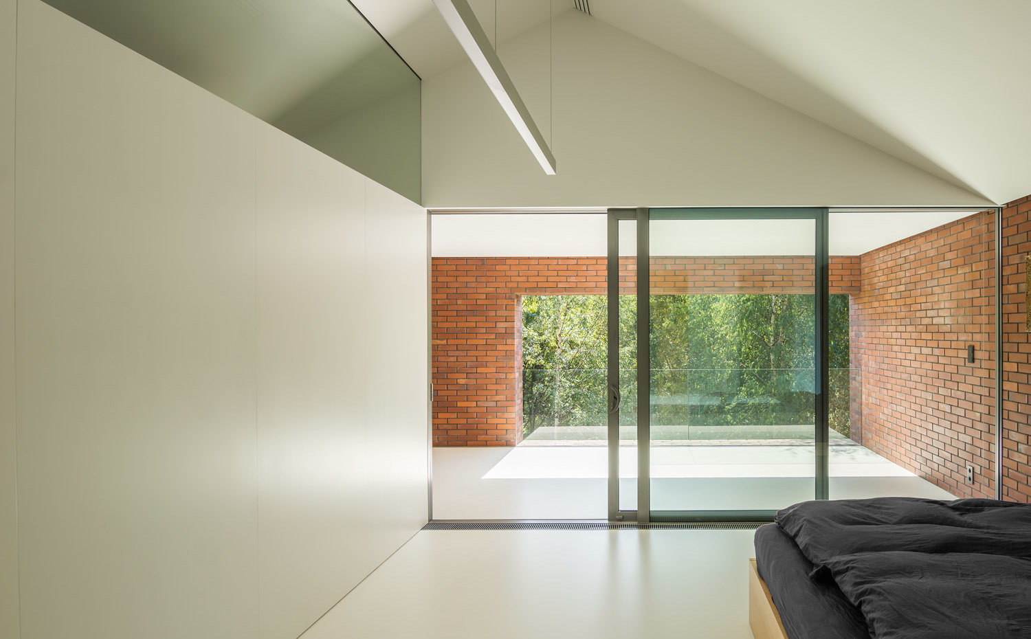 21 photo-Jakub-Certowicz Living-Garden-House-in-Katowice Robert-Konieczny-KWK-Promes. En las habitaciones se aprovecha la separación natural que provoca el tejado de dos aguas para separar el ambiente de descanso del baño. Sobre la base de la pared separadora se ha colocado un cristal