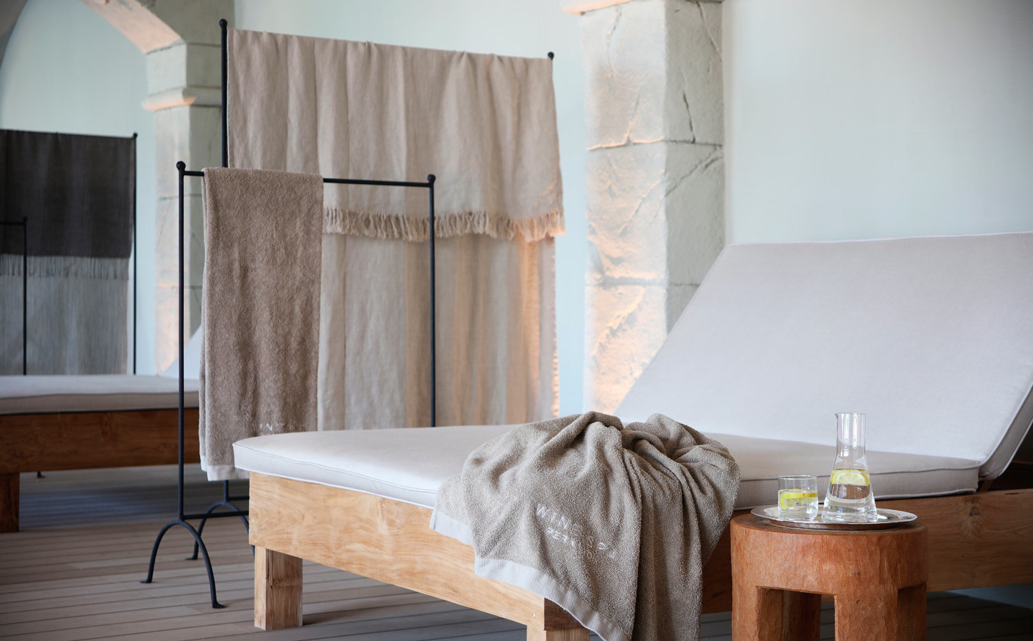 PERALADA-(3). Los colgadores metálicos con telas y toallas funcionan como separador entre mobiliario de madera recuperada y tejidos naturales de las camas perimetrales a la piscina interior 
