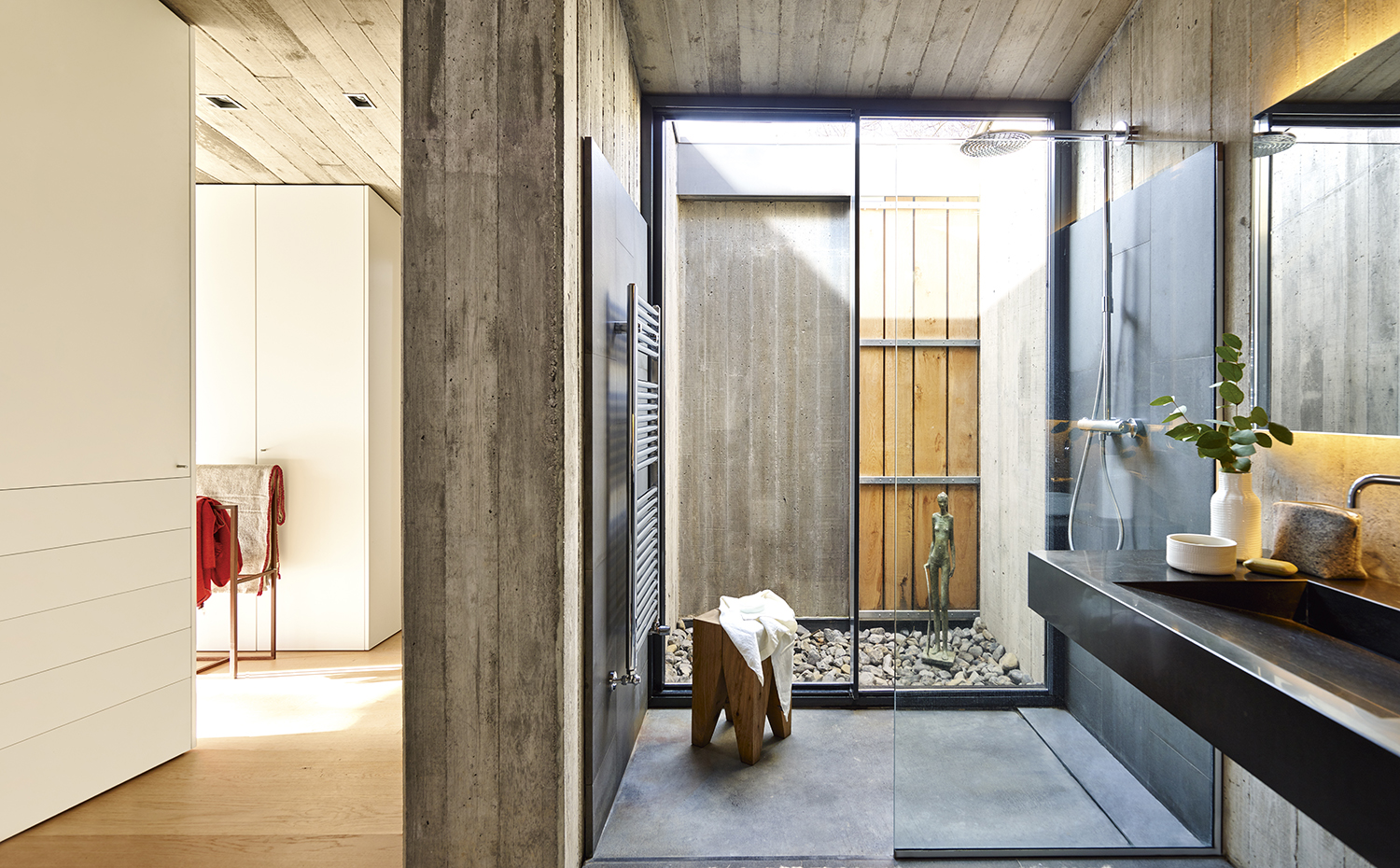 00398123 ok. Los pavimentos, revestimientos y lavabos del baño son de piedra basáltica, una evocación de la zona volcánica donde se ubica la casa. Taburete ST04 Backenzahn, de Philipp Mainzer para e15