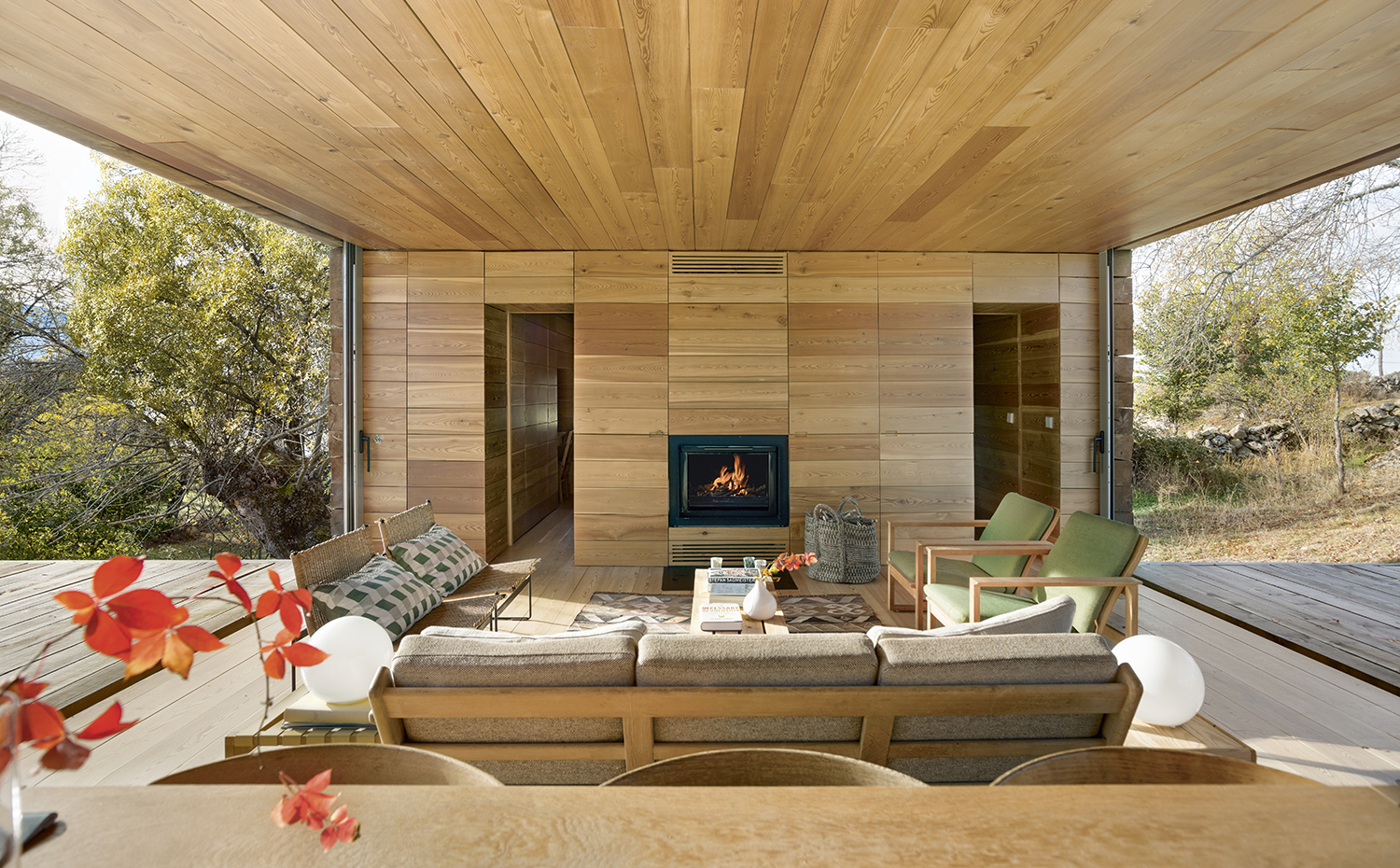 00426708 ok. Las amplias aberturas laterales dan la impresión de situar el salón al aire libre. Butacas tapizadas de verde Easy Chair, de Børge Mogensen. Butacas de mimbre, de Juan de Haro. Cojines, de La Maison