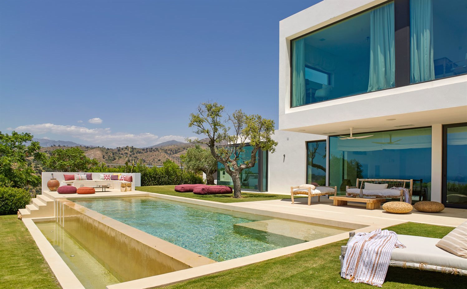 00411451 O. Junto a la piscina se ha creado una zona de chill-out, equipada con un sofá de obra y madera y decorada con cojines estampados de Nezha Kanouini y pufs, modelo Float, de Francesco Rota para Paola Lenti