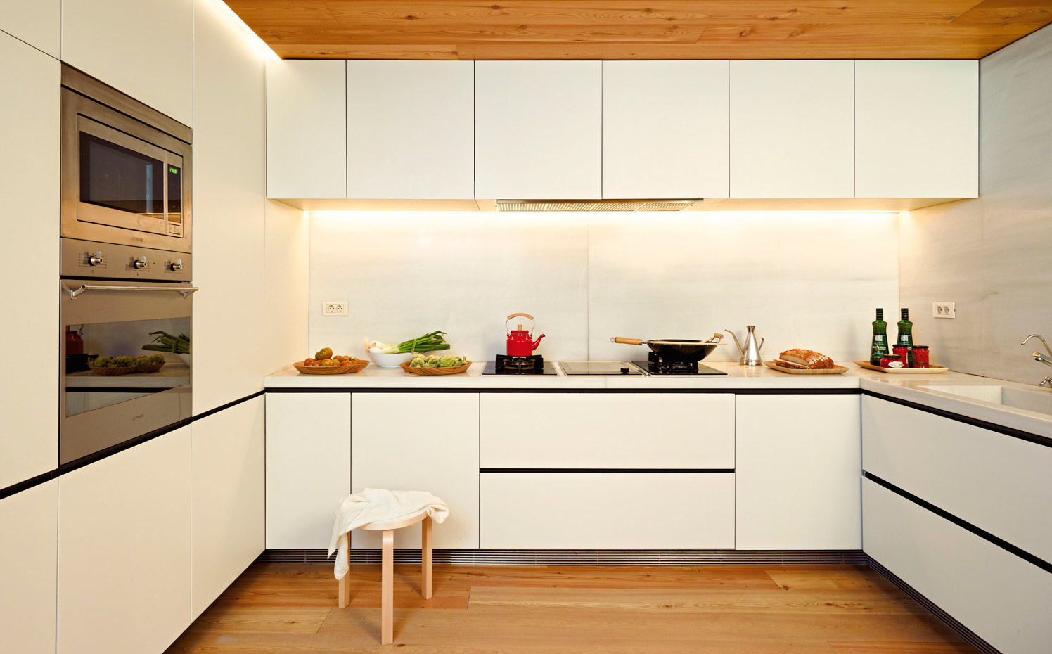 00338120. La cocina está distribuida en U. El mobiliario ha sido realizado por Carpintería Soto. Los electrodomesticos son de la marca Smeg. Taburete, de Artek.