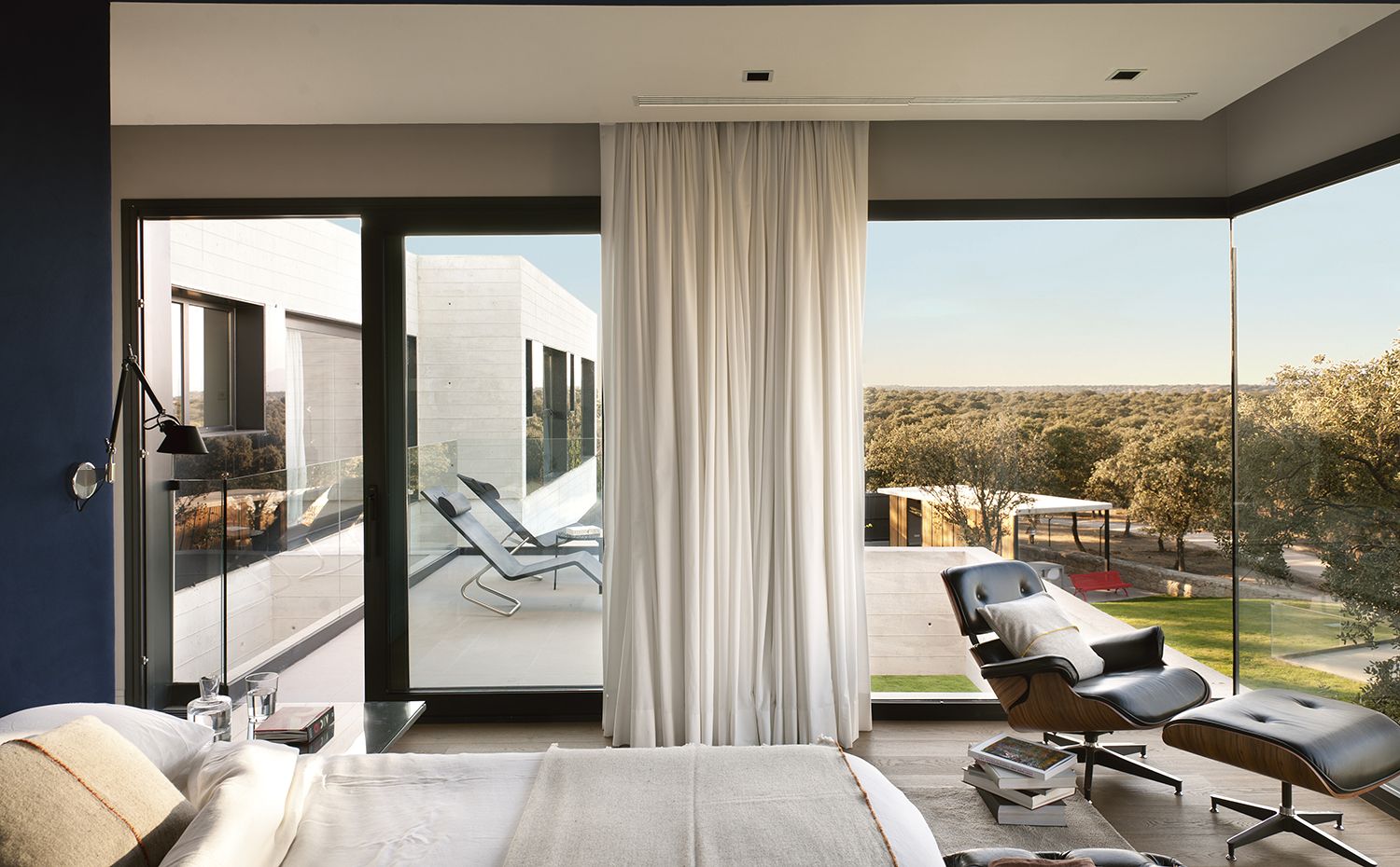 00391864. Butaca y otomana Lounge, de los Eames, editadas por Vitra. Lencería de cama y cojines, de Matèria. En la terraza, butaca MVS Chase, de Maarten van Severen
