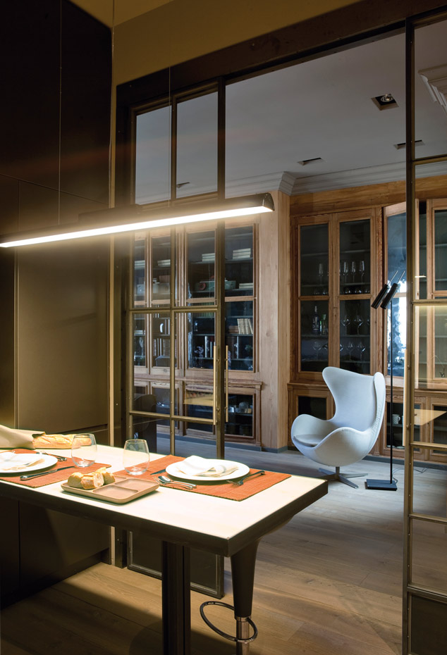 00368863. La mesa del office, de hierro y madera, es un diseño de Javier Clarós. Al fondo, la butaca Egg, de Arne Jacobsen para Fritz Hansen. La vajilla es de Villeroy & Boch