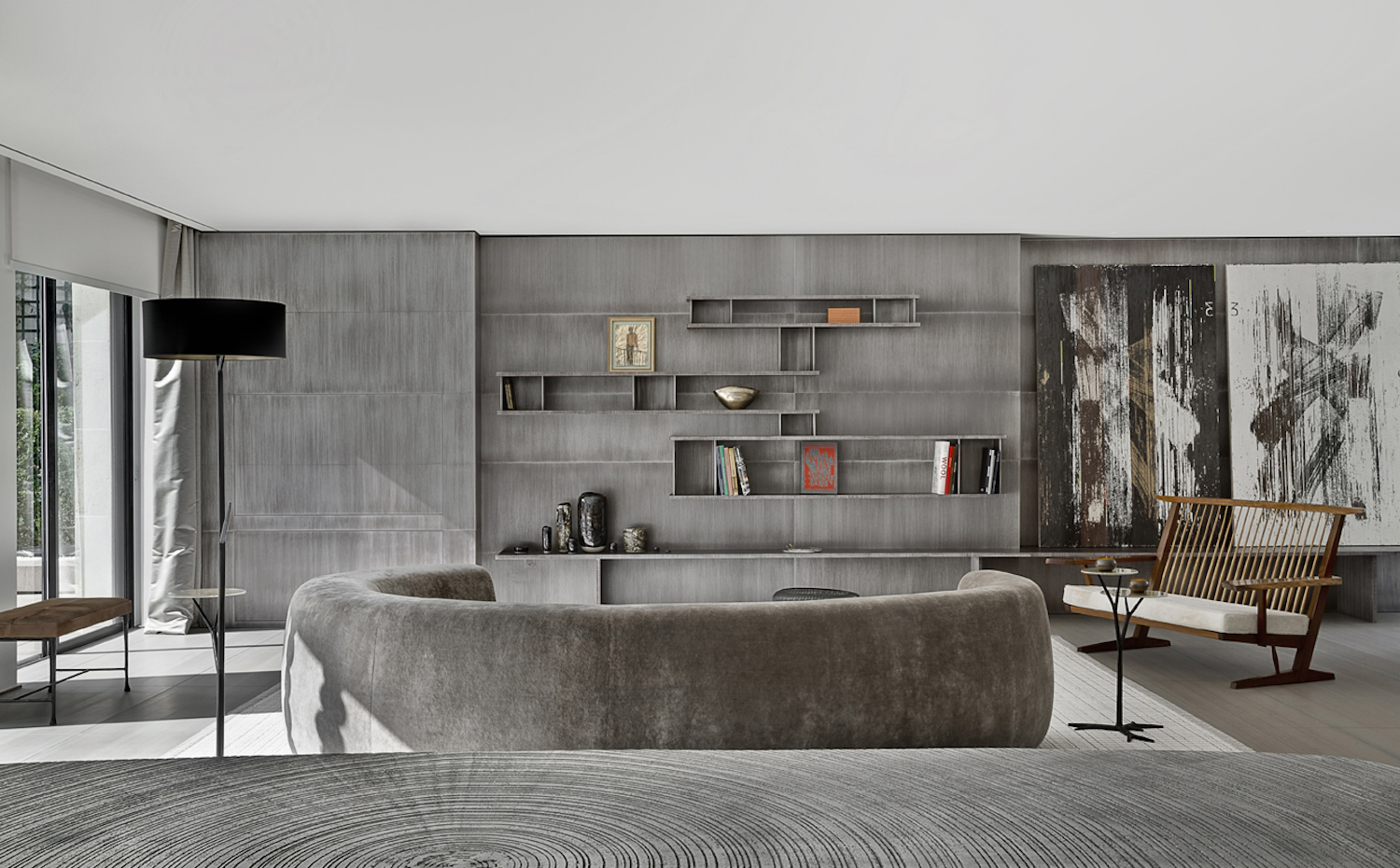 TAG61. Un sofá semicircular preside el salón. Su textura aterciopelada dialoga con la materialidad del sobre madera de la mesa, en primer término, y el panelado del mueble de pared al fondo