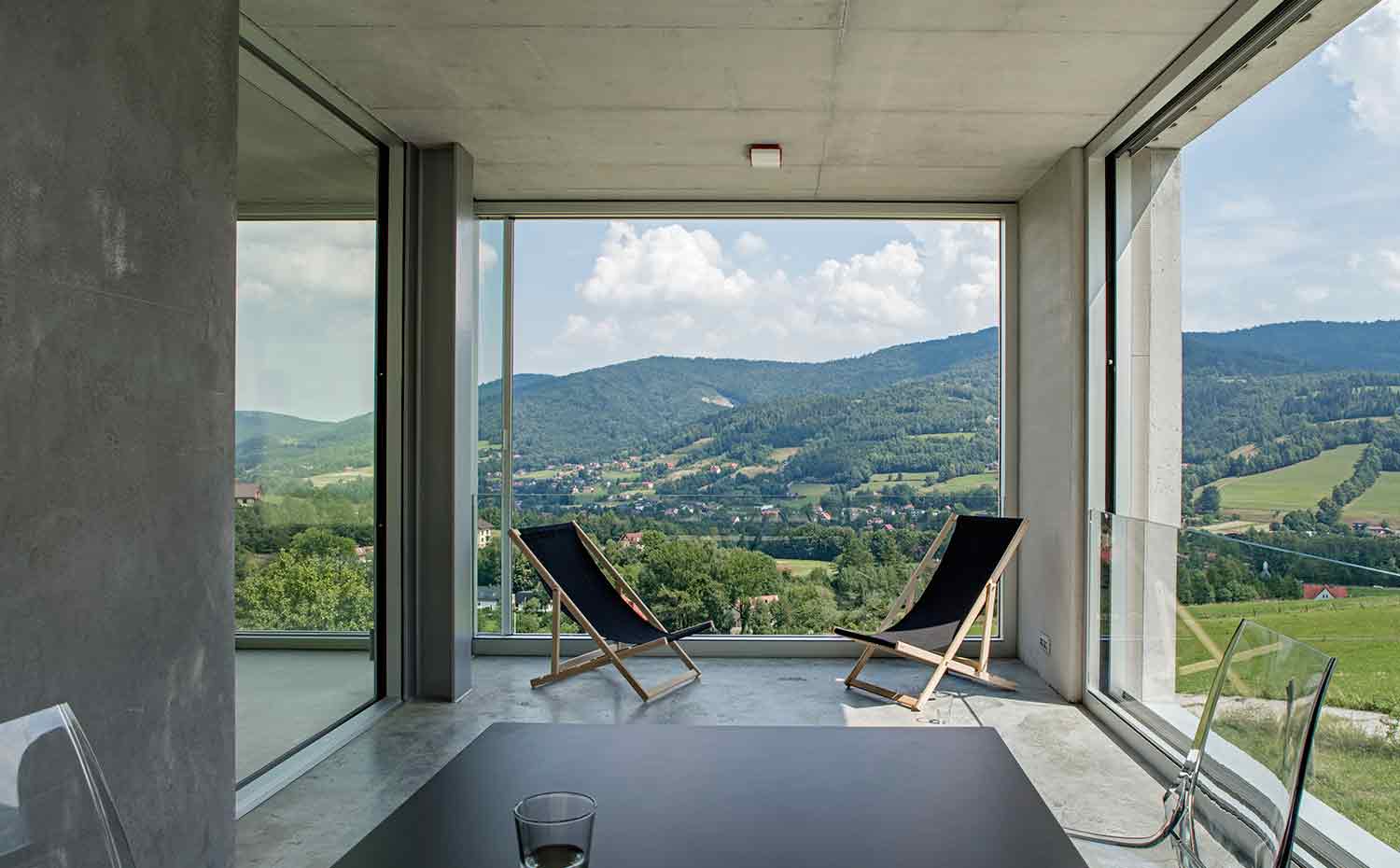 54 INTERIOR Konieczny's-Ark KWK-Promes-Robert-Konieczny photo-Olo-Studio. El valle se extiende como un lienzo detrás de las dos hamacas que se han colocado en la terraza que forma la misma casa de forma natural