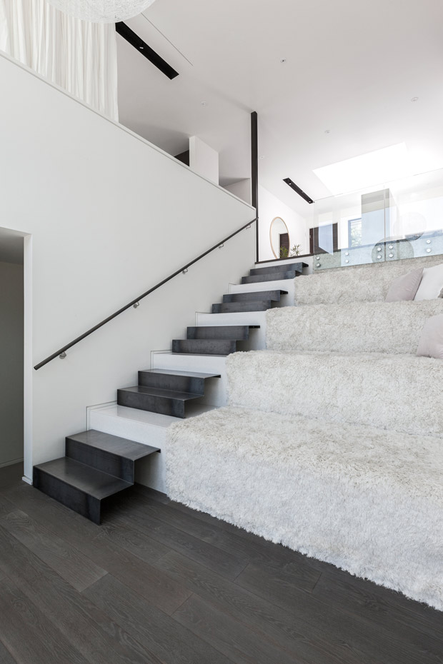Interior-Shots-02. La escalera que conduce al nivel inferior se ha dispuesto en forma de grada, forrada con un tejido mullido para poder sentarse y actuar como un espacio social, a la manera de una cómoda ágora