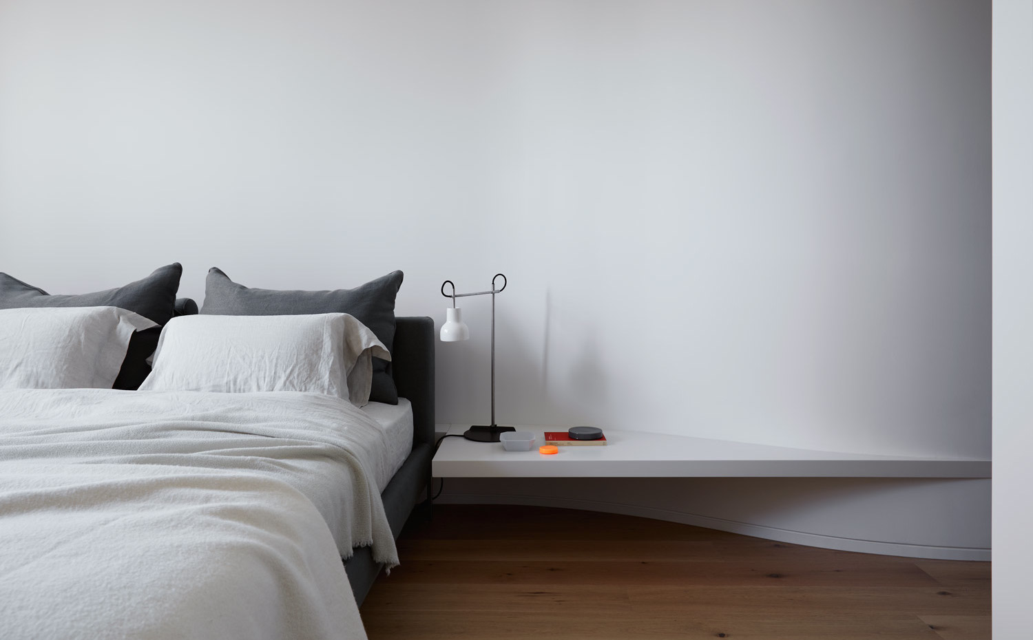 DavisAve Apt6 046. En el dormitorio principal, la pared del cabecero traza una forma curva que se aprovecha para generar un estante a modo de mesita de noche