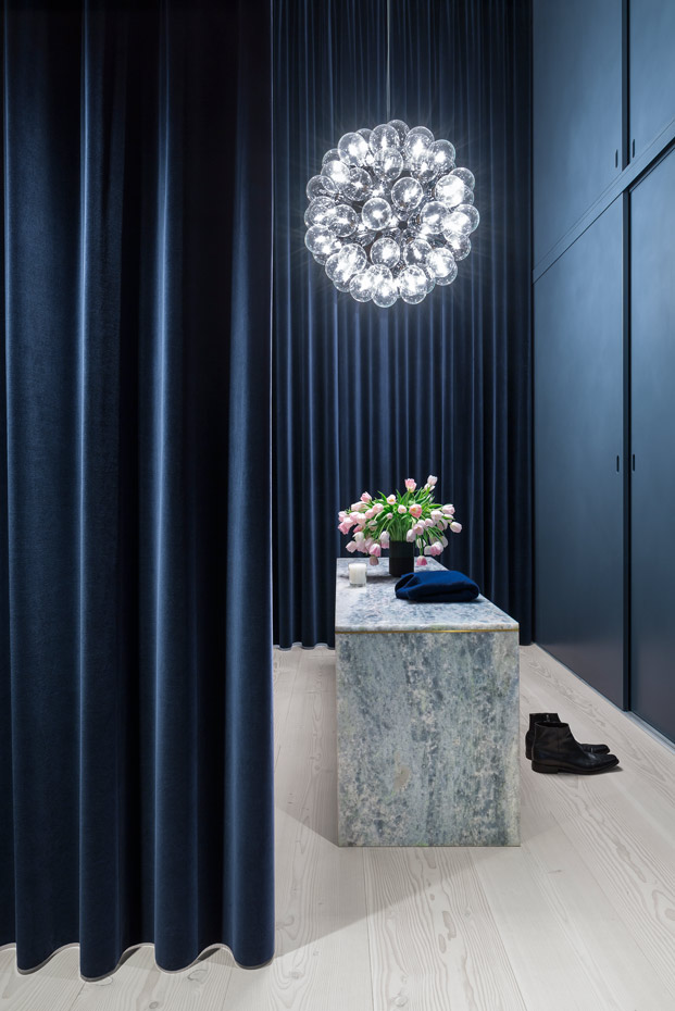 Kroyers-Plads Hampus-Berndtson 20. Las cortinas de terciopelo azul oscuro crean un efecto casi teatral en el vestidor de la suite principal. Sobre el mueble cajonero de mármol pende la lámpara Taraxacum, de Achille Castiglioni para Flos