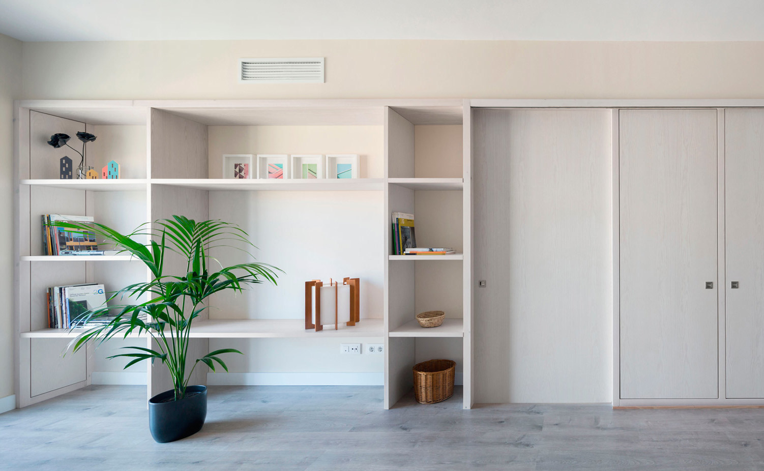 0.1. La carpintería está realizada en madera de pino con una veladura blanca para potenciar la luz natural. La estantería sin puertas contribuye a crear este efecto