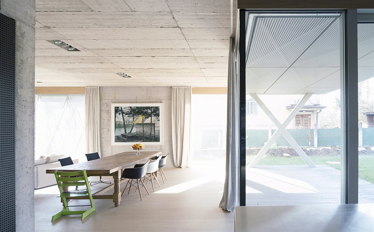 OFIS VILLA CRISS-CROSS ENVELOPE 24. Las superficies de hormigón visto sin tratar y de los suelos de madera de Listone Giordano crean la impresión de un espacio genuino, sin artificios. En el comedor, las sillas Eames Plastic Armchair DAW, de los Eames, editadas por Vitra