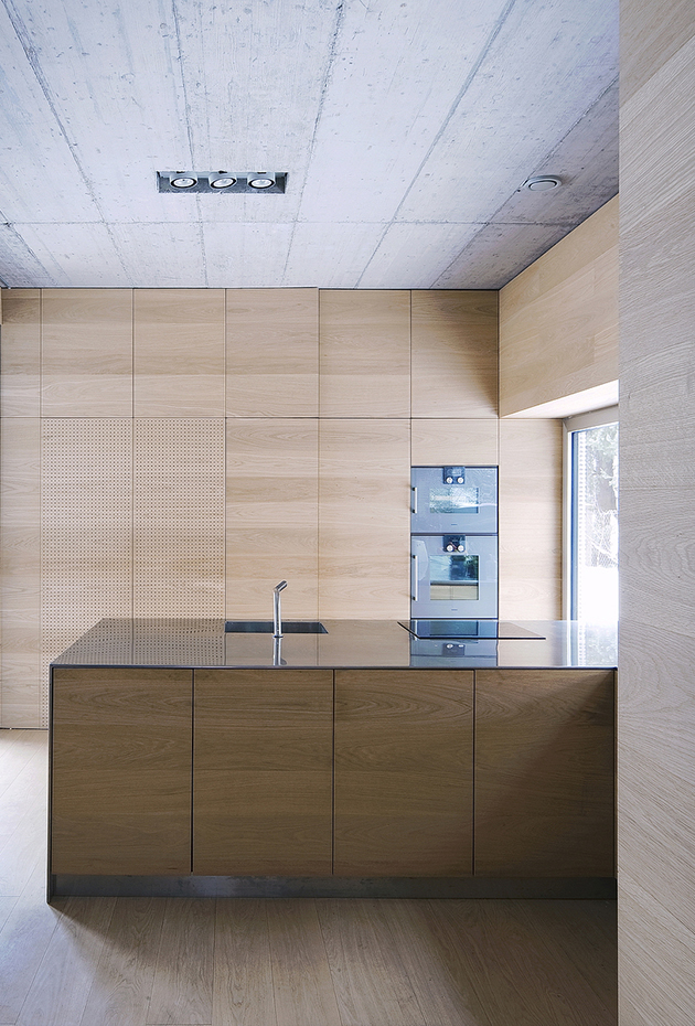 OFIS VILLA CRISS-CROSS ENVELOPE 25. En la cocina los suelos de madera se "suben" por las paredes y crean armarios a medida y una isla perfectamente integrados en el ambiente