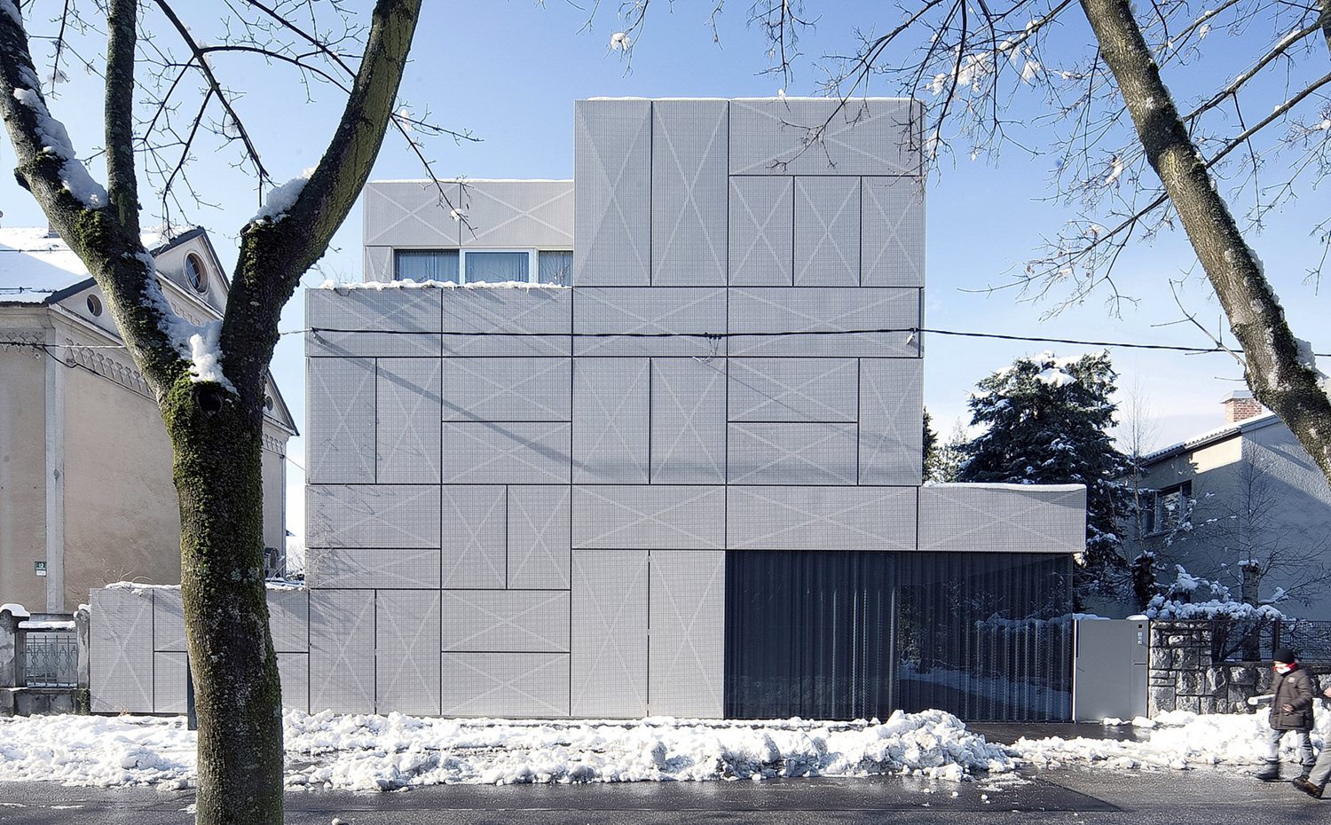OFIS VILLA CRISS-CROSS ENVELOPE 2. La casa se presenta como un volumen compacto de formas cúbicas. La fachada recubierta de paneles metálicos perforados crea un juego de líneas geométricas perpendiculares y diagonales