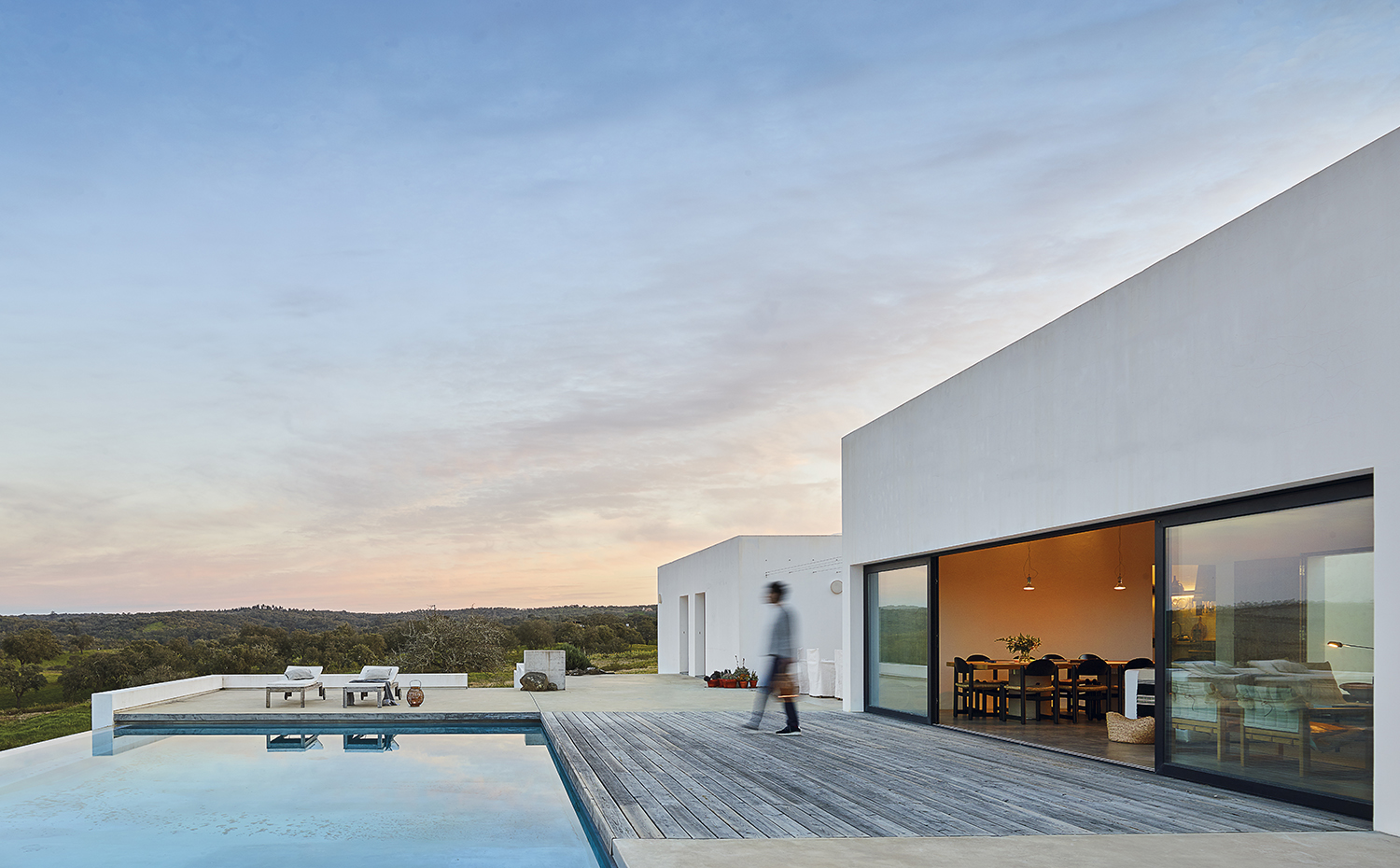 00433150. La ubicación de la casa, ligeramente elevada sobre el terreno, permite disfrutar de amplias panorámicas de las suaves colinas que la rodean. Terrazas de hormigón y de tarima de pino flanquean la piscina infinity