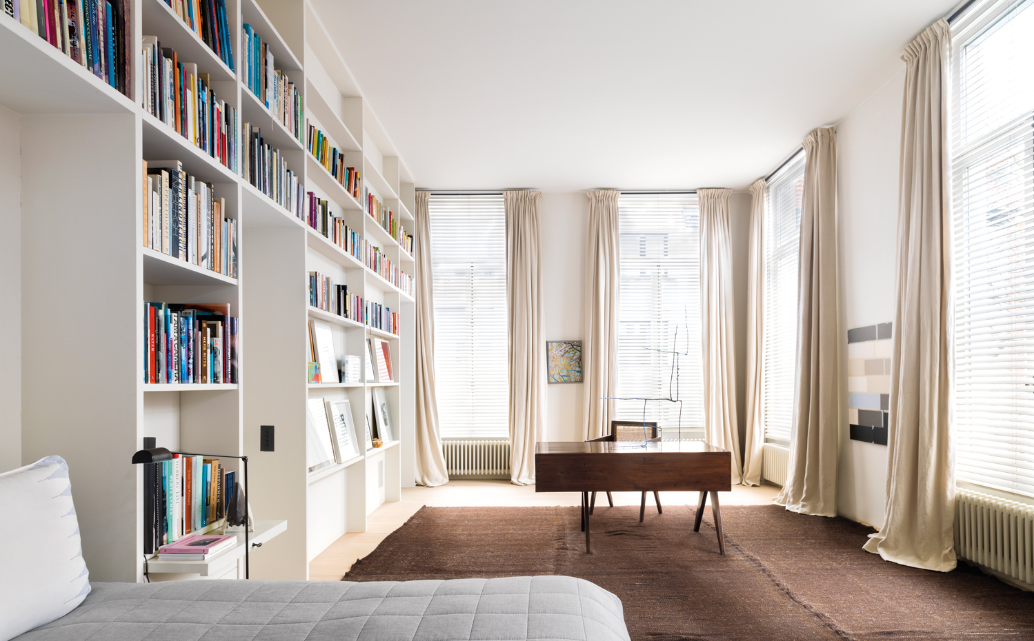 00439638. Como en otras estancias de la casa, el dormitorio principal se alimenta de luz natural por medio de hileras de ventanas vestidas con cortinas de lino. Un escritorio fechado en los años 50 convive con una librería a medida, lacada de blanco, que tapiza la pared de libros