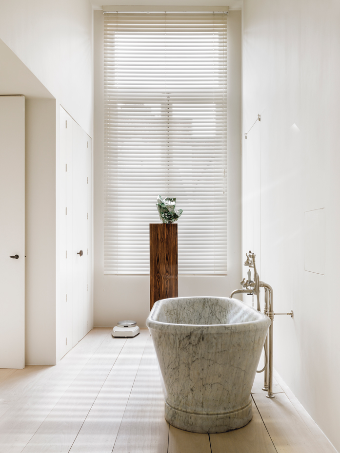 00439639. Una antigua bañera exenta, de mármol macizo, protagoniza el baño. La pieza se ha ubicado de forma que reciba luz desde la ventana y pueda ser visible desde el dormitorio a través de la puerta entreabierta
