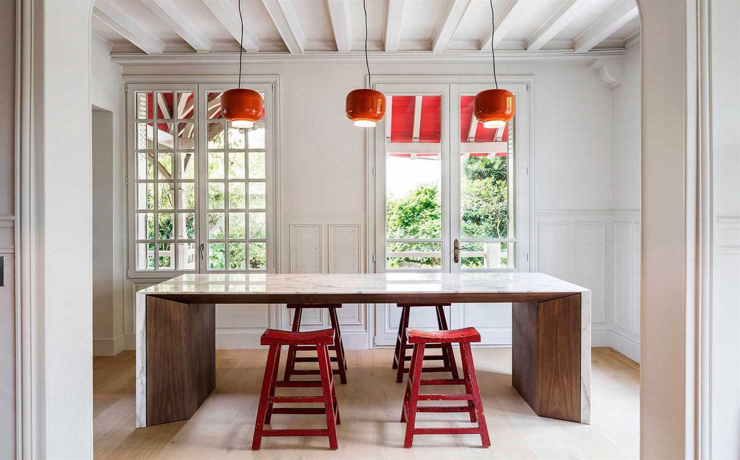 05Am 18. Junto a la cocina, una mesa de mármol y madera, con taburetes antiguos y lámparas de inspiración pop