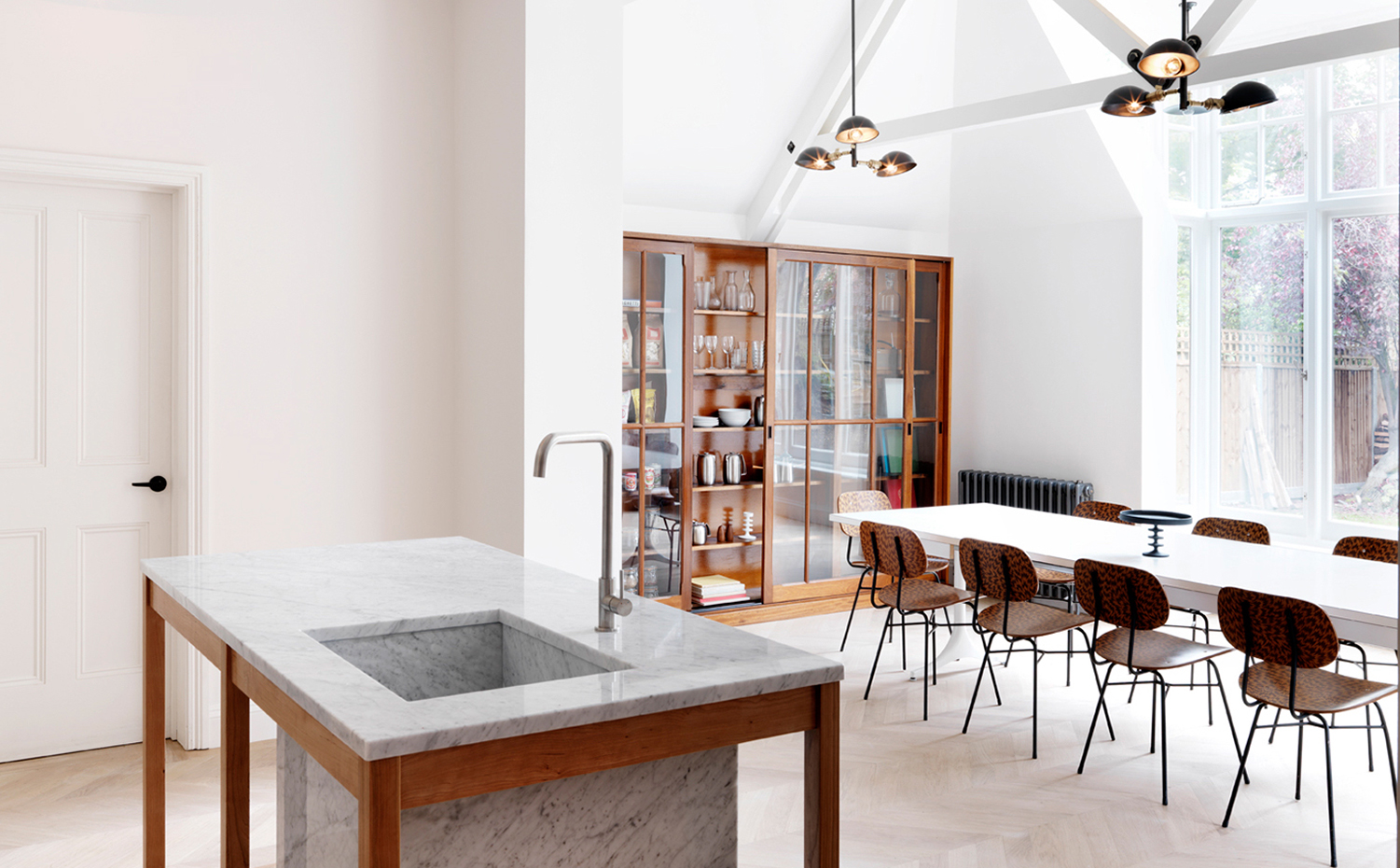 west-london-house-maclean-interiors-interiors-residential-uk dezeen hero. El comedor con vistas al jardín, está presidido por una gran mesa blanca y sillas funcionales