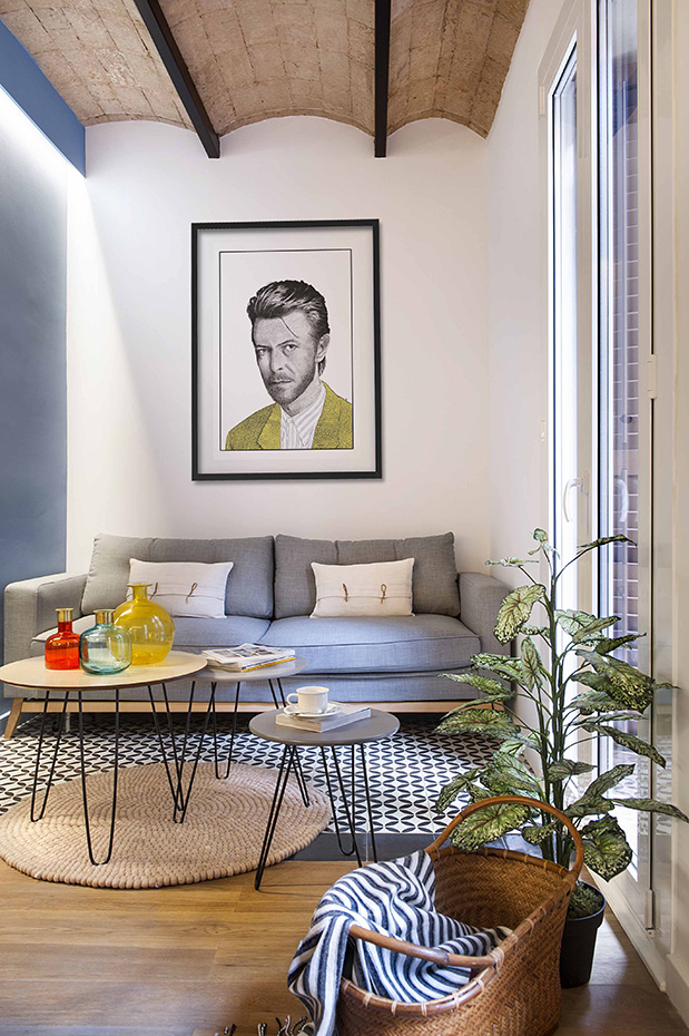 BARCELONETA 11b. Bajo el retrato de David Bowie, el sofá Brooke, de Maisons du Monde, al igual que las mesas auxiliares Graphik. Alfombra, de Sukhi