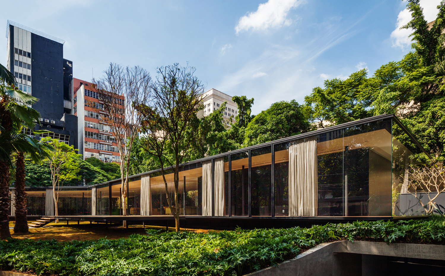 La finca, situada en un barrio de São Paulo, está rodeada de edificios. Un sótano técnico se camufla en el jardín como zona de servicio y almacén